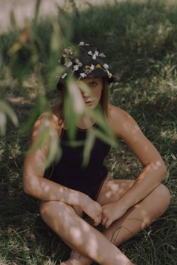 Doğanın arka planında bahar çiçeklerinden bir çelenk içinde genç ve güzel bir kız. Bir perinin güzelliği