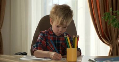 Sevimli küçük çocuk renk figürleri çiziyor. Evde Çocuk Mesafesi Öğrenme. Anaokulu çocuğu 4K no 'lu odanın yanındaki masada oturuyor.