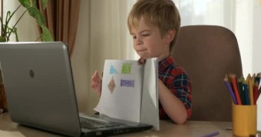 Bilgisayar kullanarak Çocuk Çalışmaları Çevrimiçi Ders Video Konferansı Sohbeti. Evde Çocuk Mesafesi Öğrenme. Anaokulu çocuğu 4K no 'lu odanın yanındaki masada oturuyor.