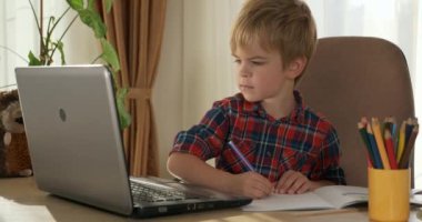 Bilgisayar kullanarak Çocuk Çalışmaları Çevrimiçi Ders Video Konferansı Sohbeti. Evde Çocuk Mesafesi Öğrenme. Anaokulu çocuğu 4K no 'lu odanın yanındaki masada oturuyor.