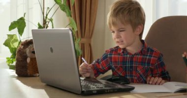 Bilgisayar kullanarak Çocuk Çalışmaları Çevrimiçi Ders Video Konferansı Sohbeti. Evde Çocuk Mesafesi Öğrenme. Anaokulu çocuğu 4K no 'lu odanın yanındaki masada oturuyor.