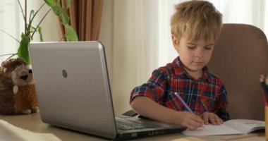 Bilgisayar kullanarak Çocuk Çalışmaları Çevrimiçi Ders Video Konferansı Sohbeti. Evde Çocuk Mesafesi Öğrenme. Anaokulu çocuğu 4K no 'lu odanın yanındaki masada oturuyor.