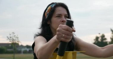 Çocuk parkında ağırlık çalıştırma antrenmanı yapan genç bir kadın. Kırsal Futbol Sahasında Güzel Kadın Vücut Çalışması. Futbol Sahası. Yaz sabahı 4K