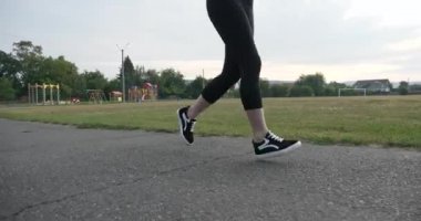 Güzel genç kadın sabah egzersizi yaparak koşuyor. Güzel Kız Formda Kadın Sporcu. Kenar mahallelerde futbol sahası var. Yaz Günü 4K