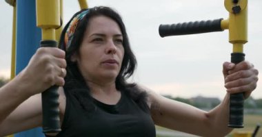 Çocuk parkında ağırlık çalıştırma antrenmanı yapan genç bir kadın. Kırsal Futbol Sahasında Güzel Kadın Vücut Çalışması. Futbol Sahası. Yaz sabahı 4K