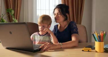 Anne Çocuk Çalışmaları İnternette Laptop Bilgisayarını Kullanarak Öğret. Küçük Çocuk Evde Mesafe Öğreniyor. Anaokulu çocuğu 4K no 'lu odanın yanındaki masada oturuyor.