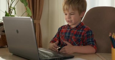 Bilgisayar kullanarak Çocuk Çalışmaları Çevrimiçi Ders Video Konferansı Sohbeti. Evde Çocuk Mesafesi Öğrenme. Anaokulu çocuğu 4K no 'lu odanın yanındaki masada oturuyor.