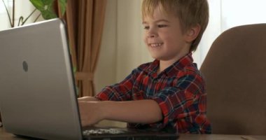 Bilgisayar kullanarak Çocuk Çalışmaları Çevrimiçi Ders Video Konferansı Sohbeti. Evde Çocuk Mesafesi Öğrenme. Anaokulu çocuğu 4K no 'lu odanın yanındaki masada oturuyor.