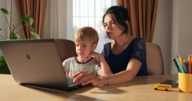 Anne Çocuk Çalışmaları İnternette Laptop Bilgisayarını Kullanarak Öğret. Küçük Çocuk Evde Mesafe Öğreniyor. Anaokulu çocuğu 4K no 'lu odanın yanındaki masada oturuyor.