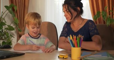 Genç Anne, Çocuk Ödevleri Dersine Yardım Ediyor. Küçük Çocuk Evde Mesafe Öğreniyor. Anaokulu çocuğu 4K no 'lu odanın yanındaki masada oturuyor.