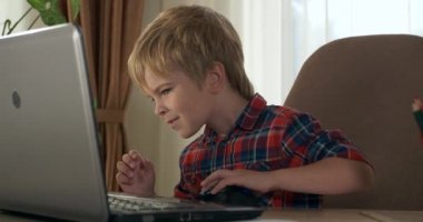 Bilgisayar kullanarak Çocuk Çalışmaları Çevrimiçi Ders Video Konferansı Sohbeti. Evde Çocuk Mesafesi Öğrenme. Anaokulu çocuğu 4K no 'lu odanın yanındaki masada oturuyor.