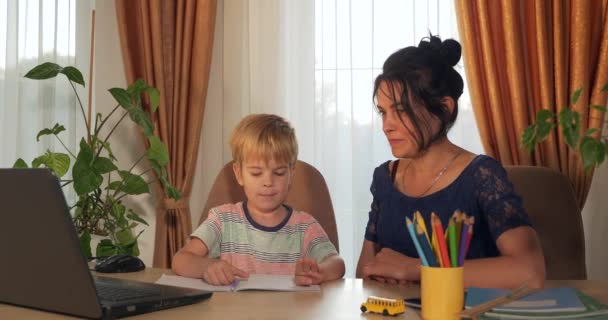 어머니는 자녀에게 숙제를 줍니다 소년은 집에서 배우는 초등학생 가까이에 데스크 — 비디오