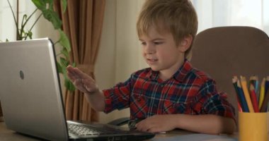 Akıllı küçük çocuk çalışmak için dizüstü bilgisayar kullanıyor. Evde Çocuk Mesafesi Öğrenme. Anaokulu çocuğu 4K no 'lu odanın yanındaki masada oturuyor.