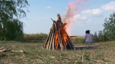 Kamp alanında, Field Plains 'deki Kamp Gölü' nün yakınında, yakın plan ateş yakma odunu. Kırsal Kır Sahnesi. Yaz Gecesi 4K