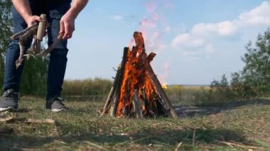 Yakın çekim Man Lights Fire Make Kamp Ateşi. Field 'daki Piknik Gölü' nün yakınında aile gezisi. Doğa Ülkesi Kırsal Sahne Yaz Günü 4K