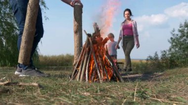 Yakın çekim Man Lights Fire Make Kamp Ateşi. Field 'daki Piknik Gölü' nün yakınında aile gezisi. Doğa Ülkesi Kırsal Sahne Yaz Günü 4K