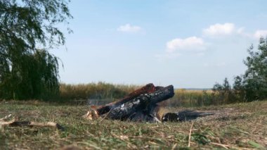 Kamp alanında, Field Plains 'deki Kamp Gölü' nün yakınında, yakın plan ateş yakma odunu. Kırsal Kır Sahnesi. Yaz Gecesi 4K