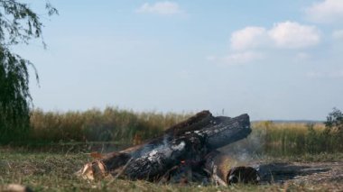 Kamp alanında, Field Plains 'deki Kamp Gölü' nün yakınında, yakın plan ateş yakma odunu. Kırsal Kır Sahnesi. Yaz Gecesi 4K