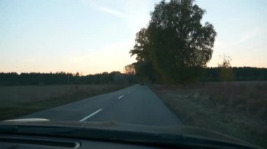 Sürücü POV ön cam aracı ön ekran araba kaputu. Autumn Evening Sunset Highway Country Road Pled Field yakınlarında. 2x Yavaş çekim 60fps 4K