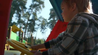 Şehir parkında oyun parkında oynayan sevimli direksiyonlu çocuk. Parlak Güneşli Yaz Günü. 2x Yavaş çekim 60fps 4K