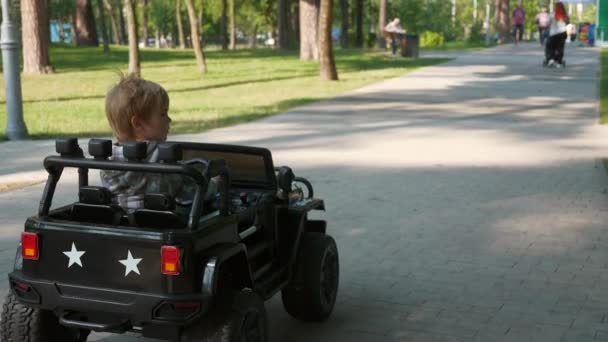 幸せな子供は公園で電動おもちゃの車に乗るを運転します 興奮した子供の少年 夏の朝の晴れた日 2倍スローモーション60 Fps — ストック動画