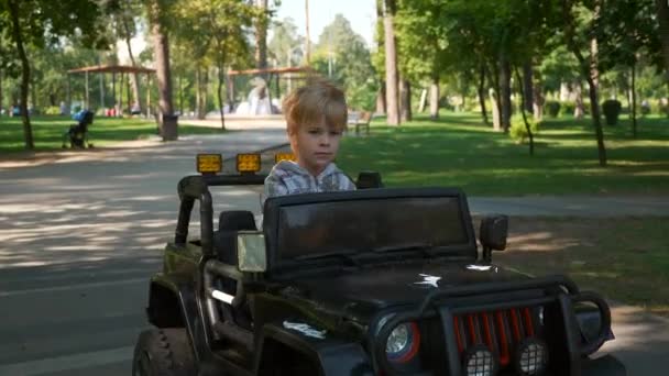 Happy Child Drives Ηλεκτρική Powered Toy Car Ride Στο Πάρκο — Αρχείο Βίντεο