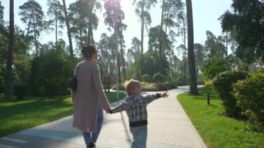 Anne Çocuk Yürüyüşü Parkı 'nda. Kid Boy 'la birlikte Güzel Doğa' da Dinlenen Kadın. Yaz sabahı güneşli bir gün. Yavaş çekim 4K
