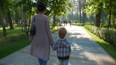 Anne Çocuk Yürüyüşü Parkı 'nda. Kid Boy 'la birlikte Güzel Doğa' da Dinlenen Kadın. Yaz sabahı güneşli bir gün. Yavaş çekim 4K