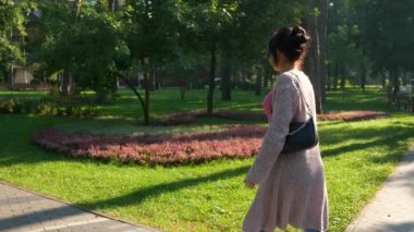 Pretty Woman Park 'ta Yürüyüş. Genç dişi dinleniyor, güzel doğada dinleniyor. Yaz sabahı güneşli bir gün. 2x Yavaş çekim 60fps 4K