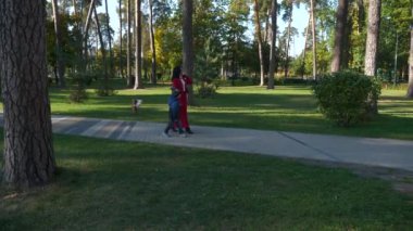 Anne ve Oğul Şehir Parkı 'nda Yürüyüş. Kadın Çocuk Çocukla Dinlen. Güneşli bir gün. 2x Yavaş çekim 60fps 4K