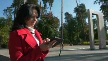 Şehir parkında internette sörf yapan kadın akıllı telefon kullanarak telefon izliyor. Ciddi Kadın Yüzü. Sonbahar Günü. 2x Yavaş çekim 60fps 4K