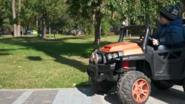 Şirin Çocuk Parkta Elektrikli Oyuncak Araba Sürüşü Yapıyor. Heyecanlı Çocuk Çocuk 'u. Sonbahar güneşli günü. 2x Yavaş çekim 60fps 4K