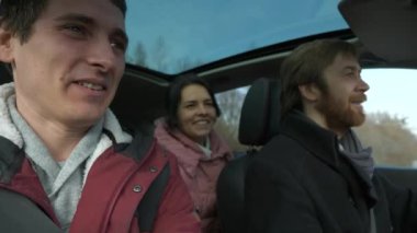 Mutlu Arkadaşlar Arabayla Birlikte Seyahat Eder. Bir grup Turist Aile Seyahati. SUV Panoramik Cam Çatı. Erkek Kadın Kış Giyimi Sonbahar Sezonu. 2x Yavaş çekim 60fps 4K