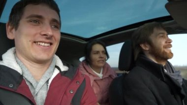 Mutlu Arkadaşlar Arabayla Birlikte Seyahat Eder. Bir grup Turist Aile Seyahati. SUV Panoramik Cam Çatı. Erkek Kadın Kış Giyimi Sonbahar Sezonu. 2x Yavaş çekim 60fps 4K