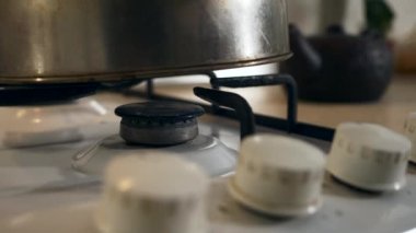 Kadın El Çevirici Tokmağı yakın plan. Gaz ocağını yakıyorum Mavi Alev Eski Metal Kettle 'ı ısıtıyorum. Mutfakta yemek pişirmek. Yavaş çekim 4K