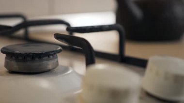 Kadın El Çevirici Tokmağı yakın plan. Gaz ocağını yakıyorum Mavi Alev Eski Metal Kettle 'ı ısıtıyorum. Mutfakta yemek pişirmek. Yavaş çekim 4K