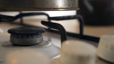 Kadın El Çevirici Tokmağı yakın plan. Gaz ocağını yakıyorum Mavi Alev Eski Metal Kettle 'ı ısıtıyorum. Mutfakta yemek pişirmek. Yavaş çekim 4K