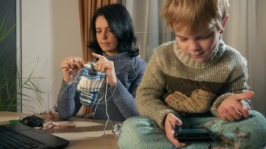 Çocuk Çocuk Akıllı Telefon İnternet Sosyal Medyası Kullanıyor. Örgü Şırıngası ile Ana Örgü Pencerenin yanında. Soğuk kış sezonu. 2x Yavaş çekim 60fps 4K
