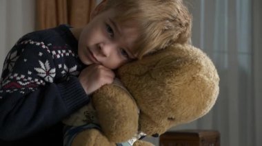 Üzgün küçük çocuk oturmuş oyuncak ayıya sarılıyor. Evde Yalnız Çocuk Bayan Ebeveynler. 2x Yavaş çekim 60 fps