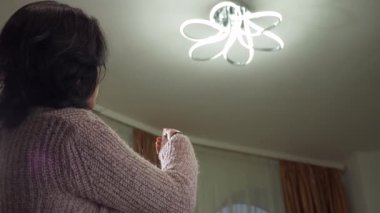 Ana odada Modern Kablosuz Aygıt kullanarak Kadın Uzaktan Kumanda ile Işık Renklerini Değiştir. Yavaş çekim