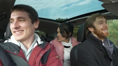 Mutlu Arkadaşlar Arabayla Birlikte Seyahat Eder. Bir grup Turist Aile Seyahati. SUV Panoramik Cam Çatı. Erkek Kadın Kış Giyimi Sonbahar Sezonu. 2x Yavaş çekim 60fps 4K
