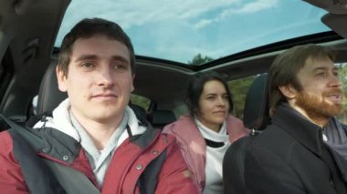 Mutlu Arkadaşlar Arabayla Birlikte Seyahat Eder. Bir grup Turist Aile Seyahati. SUV Panoramik Cam Çatı. Erkek Kadın Kış Giyimi Sonbahar Sezonu. 2x Yavaş çekim 60fps 4K