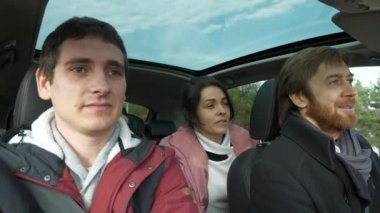 Mutlu Arkadaşlar Arabayla Birlikte Seyahat Eder. Bir grup Turist Aile Seyahati. SUV Panoramik Cam Çatı. Erkek Kadın Kış Giyimi Sonbahar Sezonu. 2x Yavaş çekim 60fps 4K