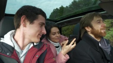 Kadın Akıllı Telefon Navigasyon Programı GPS Konumunu Kullan. Arkadaşlar Arabayla Birlikte Seyahat Eder. Bir grup Turist Aile Seyahati. SUV Panoramik Cam Çatı. Kış Giyimi Sonbaharı. 2x Yavaş çekim 60 fps 4K