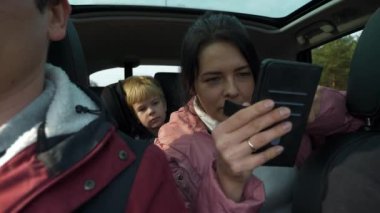 Kadın Akıllı Telefon Navigasyon Programı GPS Konumunu Kullan. Arkadaşlar Arabayla Birlikte Seyahat Eder. Bir grup Turist Aile Seyahati. SUV Panoramik Cam Çatı. Kış Giyimi Sonbaharı. 2x Yavaş çekim 60 fps 4K