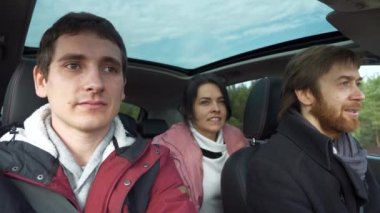 Bir grup turist arabayla seyahat ediyor. Düşünceli arkadaşlar konuşur. Yolculuk Aile Seyahati. SUV Panoramik Cam Çatı. Erkek Kadın Kış Giyimi Sonbahar Sezonu. 2x Yavaş çekim 60 fps 4K