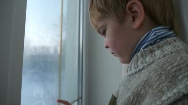 Cute Little Boy Draws with Finger on Wet Window Glass.Kid Wear Child Sweater.  Winter Season Day. 2x Slow motion 60fps 4K