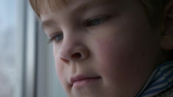 悲しい動揺小さな男の子は窓の近くに立っています 思考ロンリーキッドはミスを待つと思う 子供はセーターを着る 冬の季節の日 2倍スローモーション60Fps — ストック動画