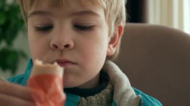 Çocuk Sosis Ye. Mutfak Masasında Yemek Yiyen Çocuk Yemeği Yemeği. Oğlan Kış Günü 'nde kalın süveter giyer. Yakın çekim 2x Yavaş çekim 60fps 4K