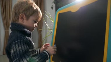 Küçük çocuk tahtasında tebeşir olan araba çiziyor. Evde Çocuk Eğitimi. Akşam Odası İçi. 2x Yavaş çekim 60fps 4K